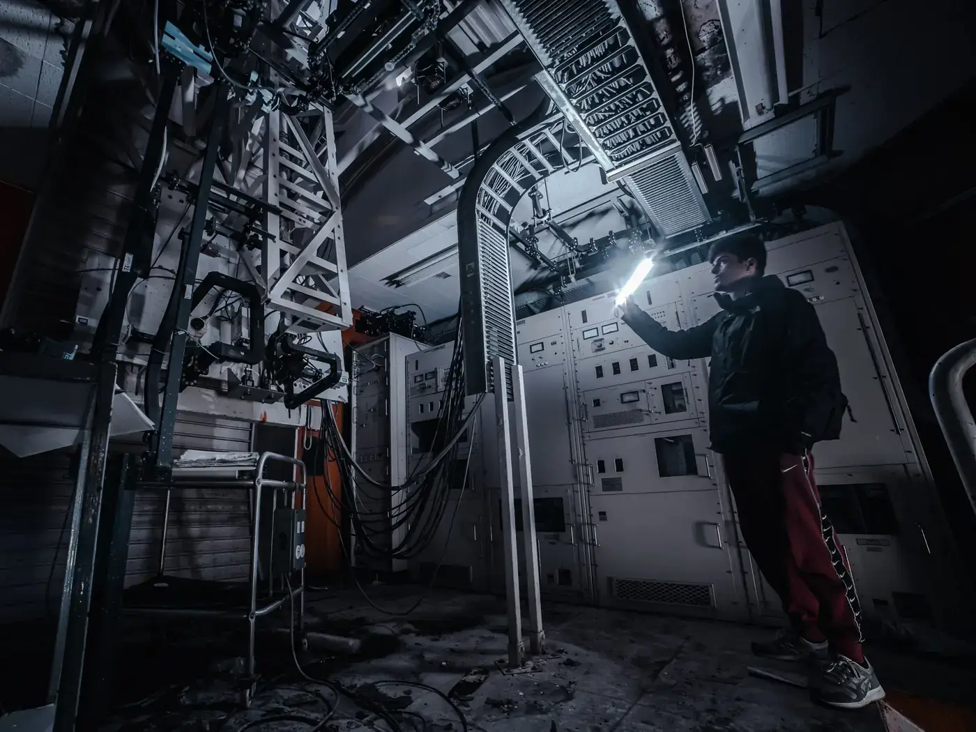 Technician shining a flashlight on equipment in a dark mechanical room
