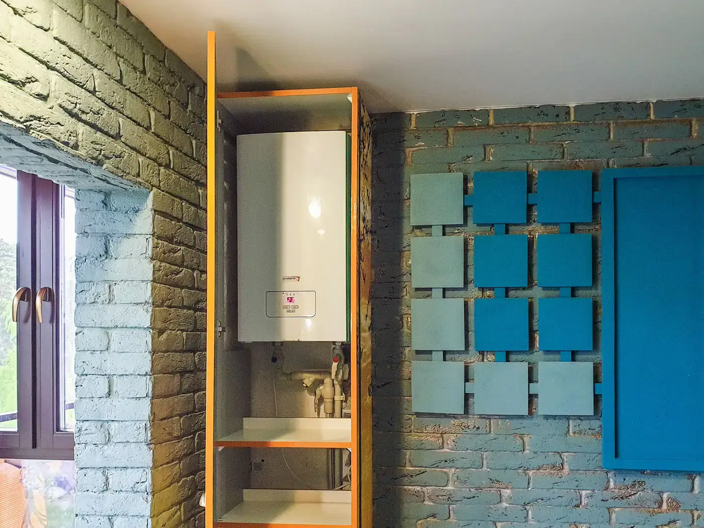 Wall-mounted white water heater tank installed in a recessed cabinet with water lines below